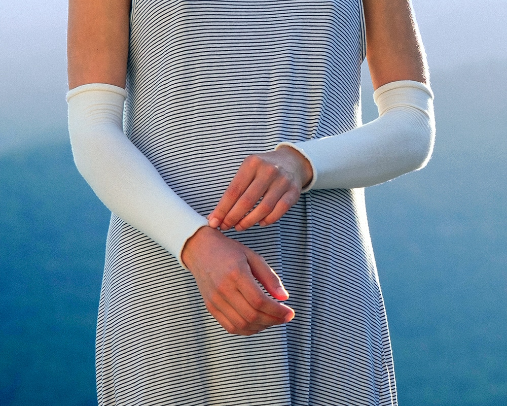 femme portant délicatement sa main gauche sur un tube de protection placé sur son bras droit. Le tube est blanc et épouse parfaitement la forme du bras du coude jusqu'au poignet.